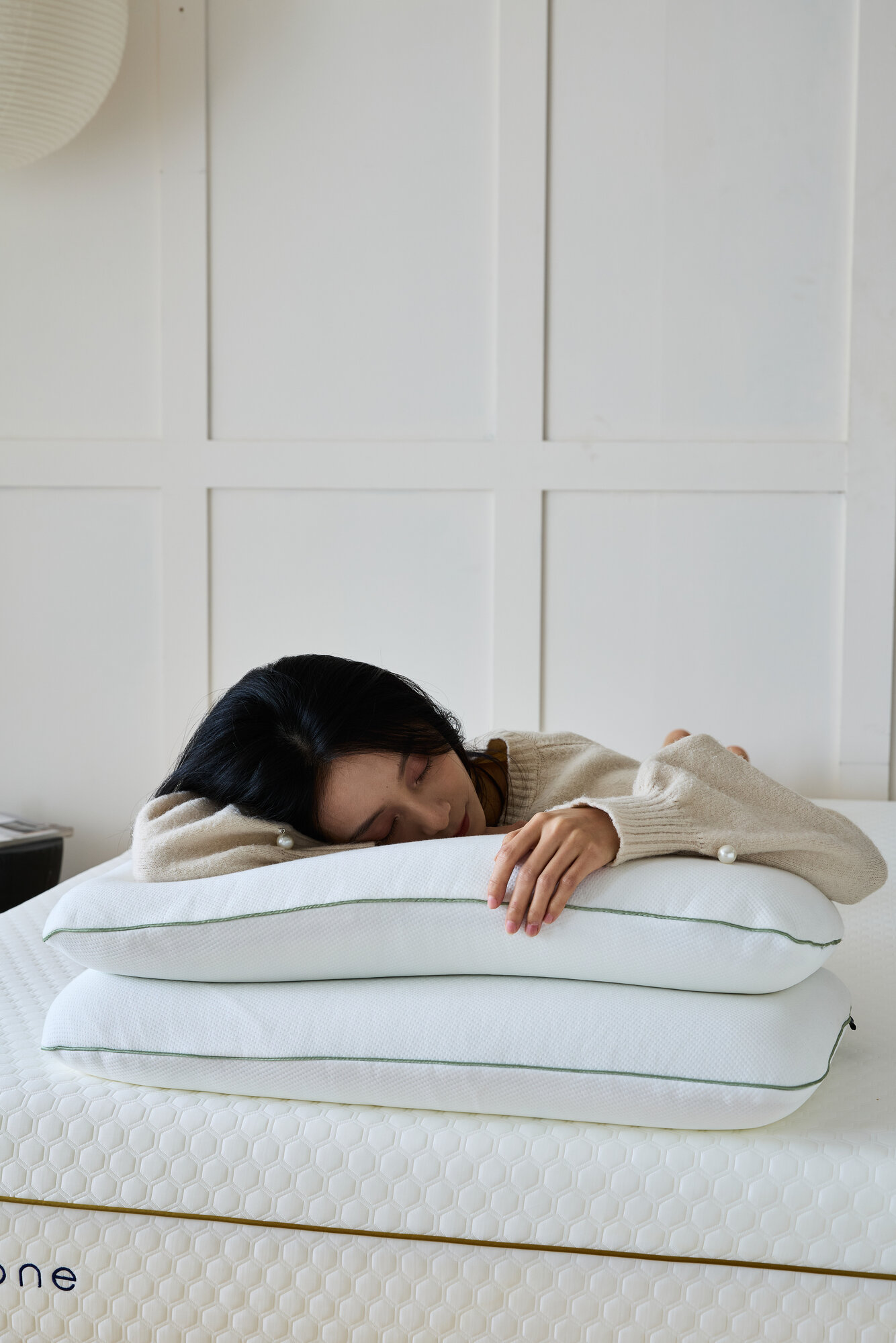 A woman asleep face down on two stacked Hybrid pillows